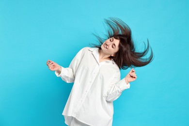 Photo of Happy woman in pyjama shaking head on light blue background