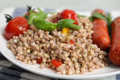 Photo of Plate with tasty buckwheat porridge and sausages, closeup