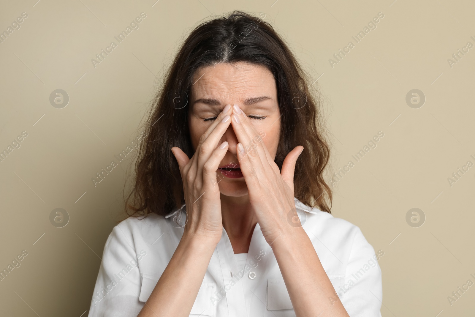 Photo of Mature woman suffering from headache on beige background