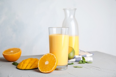 Fresh mango drink and tropical fruits on table against color background. Space for text