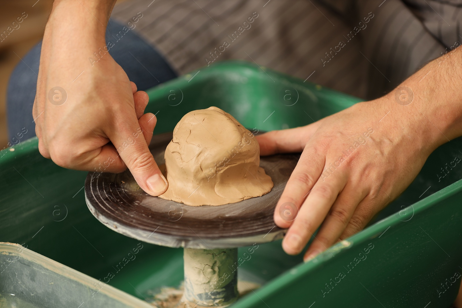 Photo of Man crafting with clay on potter's wheel, closeup