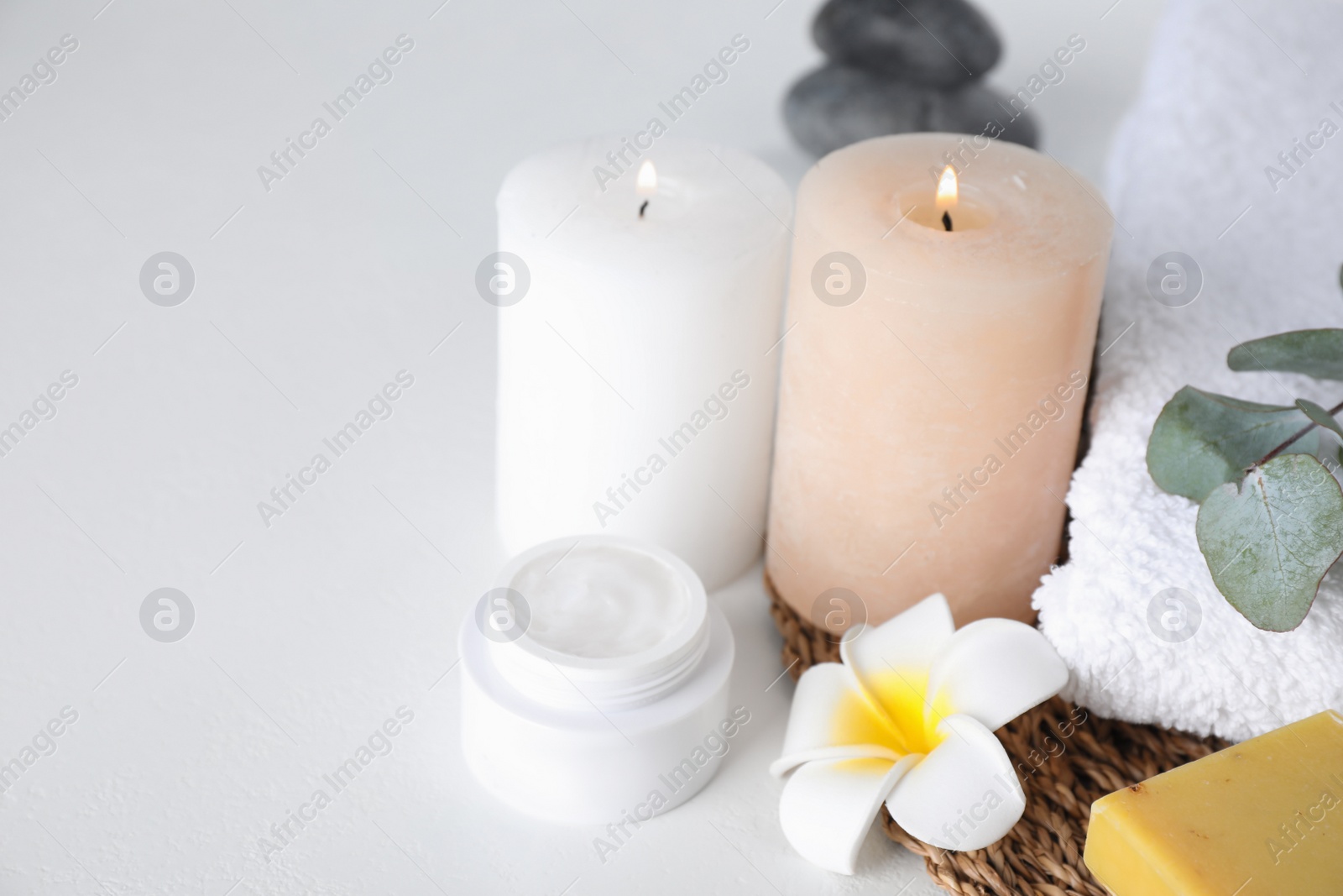 Photo of Composition with cream and burning candles on white table. Spa treatment