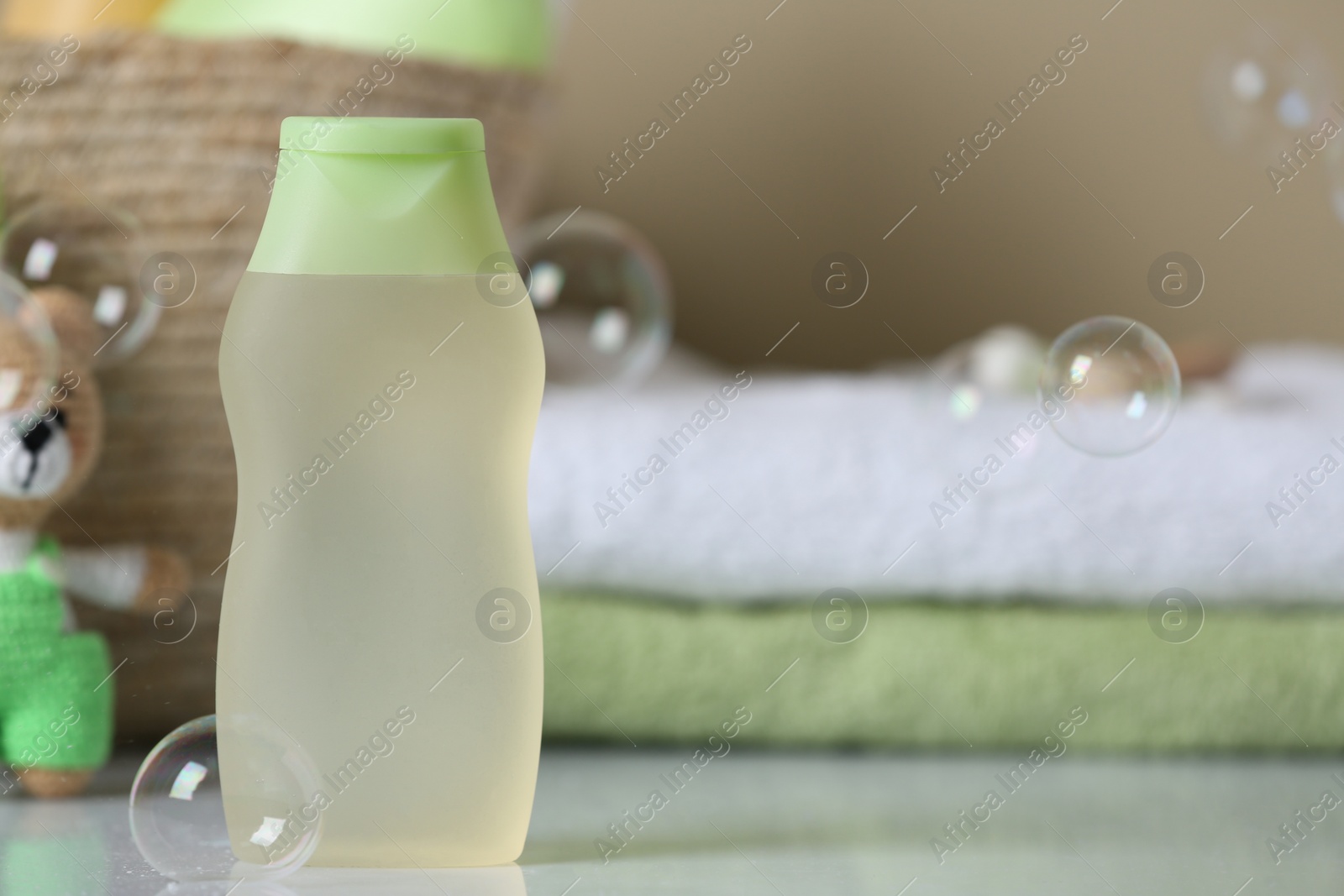 Photo of Bottle of baby cosmetic product on white table, space for text