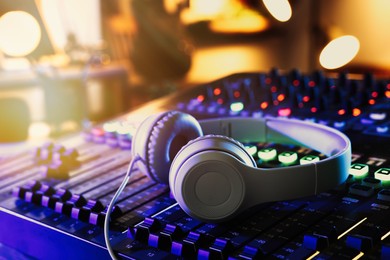 Photo of Headphones on professional mixing console in radio studio, closeup