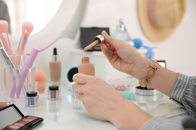 Photo of Woman applying makeup at dressing table, closeup