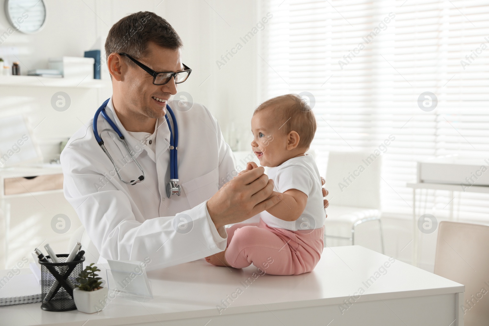 Photo of Pediatrician examining cute little baby in clinic. Space for text