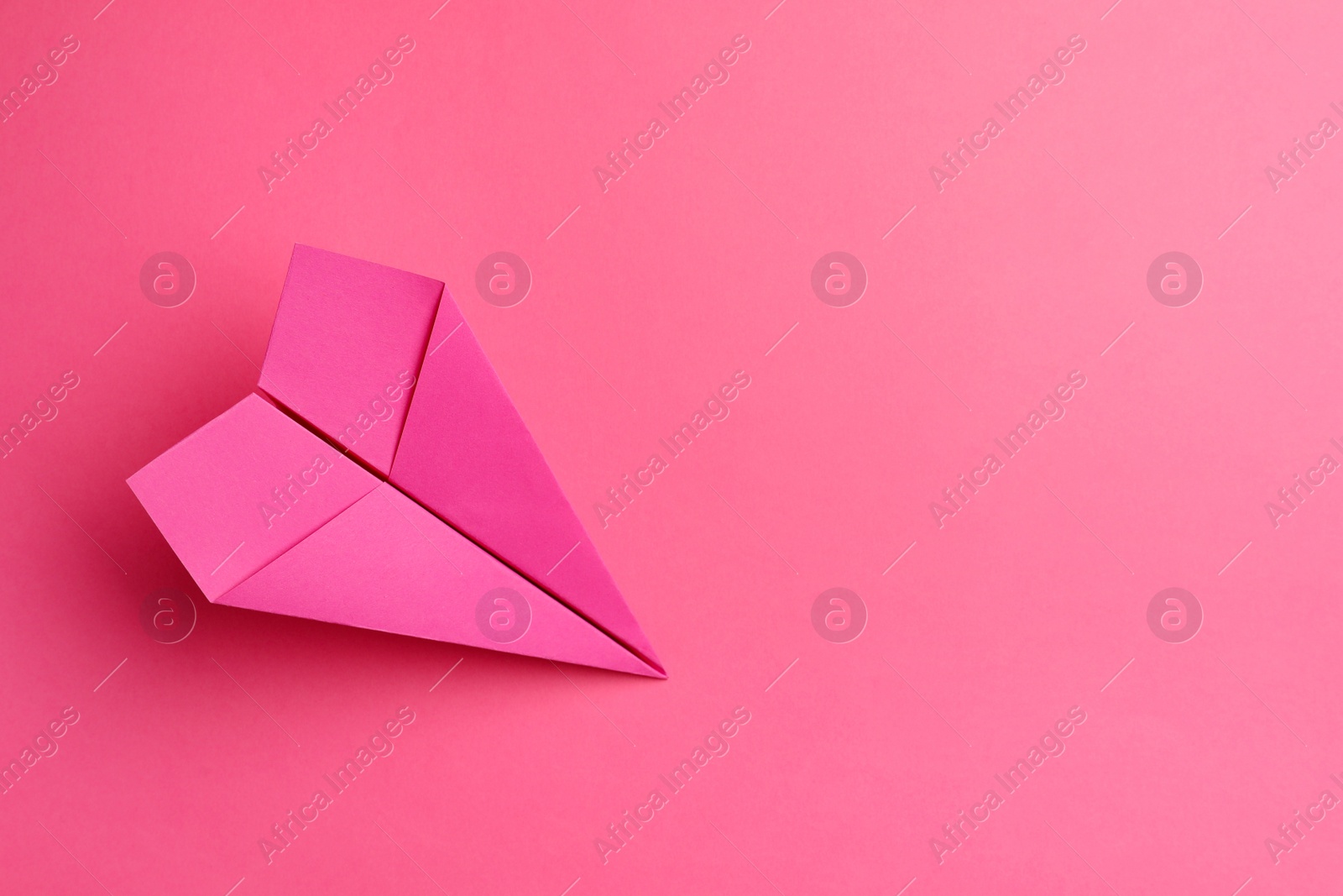 Photo of Handmade paper plane on pink background, top view. Space for text