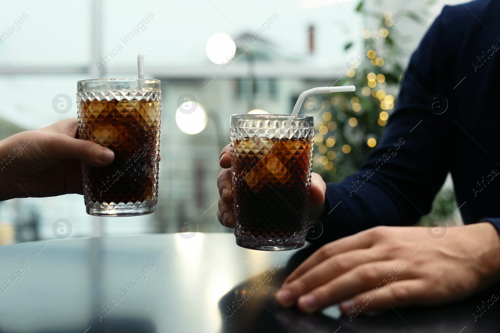 Photo of Couple with glasses of cold cola at table in cafe, closeup