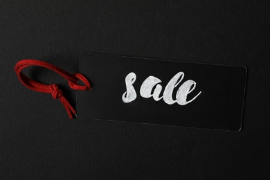 Photo of Tag with word SALE on dark background, top view. Black Friday concept