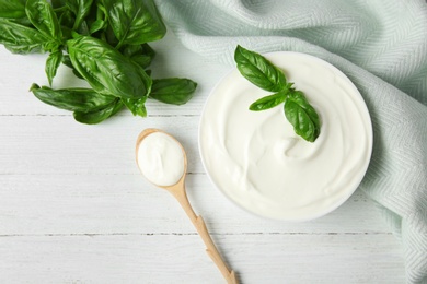 Flat lay composition with sour cream and basil on white wooden table