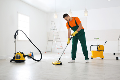 Professional janitor cleaning floor with mop after renovation
