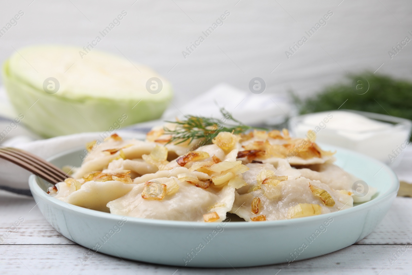 Photo of Cooked dumplings (varenyky) with tasty filling, fried onions and dill on wooden table, closeup