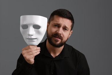Photo of Multiple personality concept. Tired man with mask on grey background