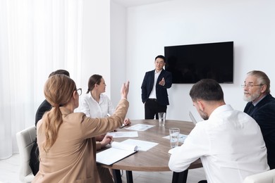 Photo of Business conference. Group of people listening to speaker report near tv screen in meeting room