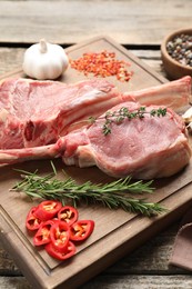 Photo of Fresh tomahawk beef cuts and spices on wooden table