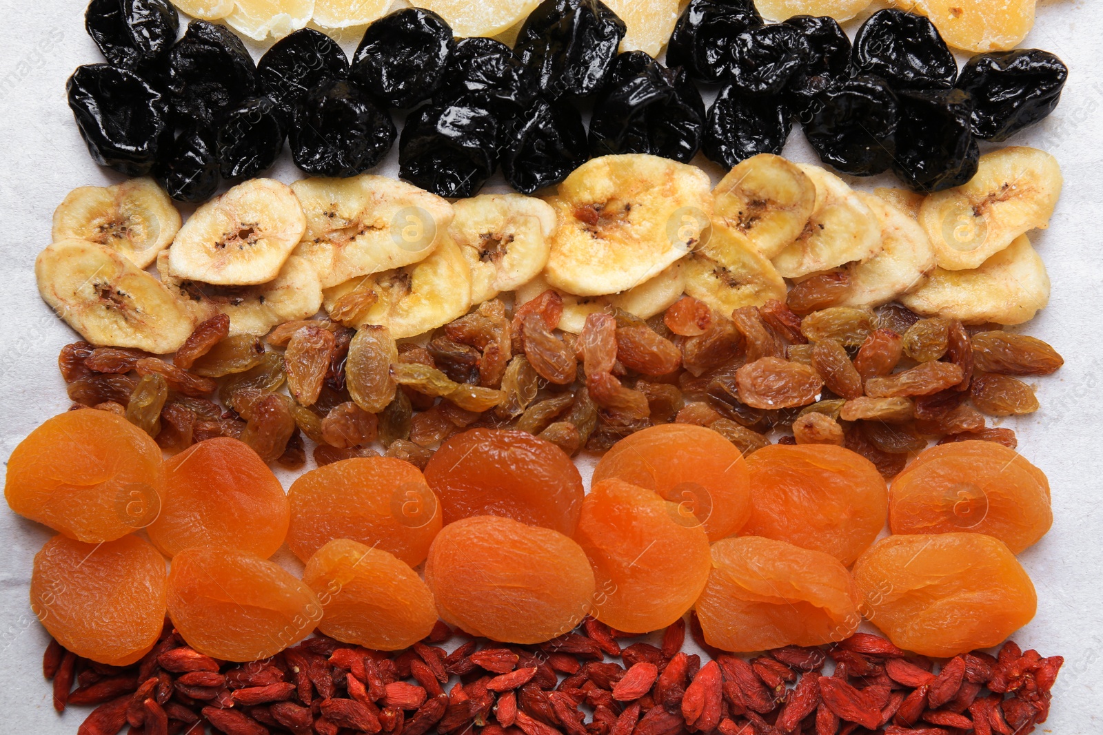 Photo of Different tasty dried fruits on paper, flat lay