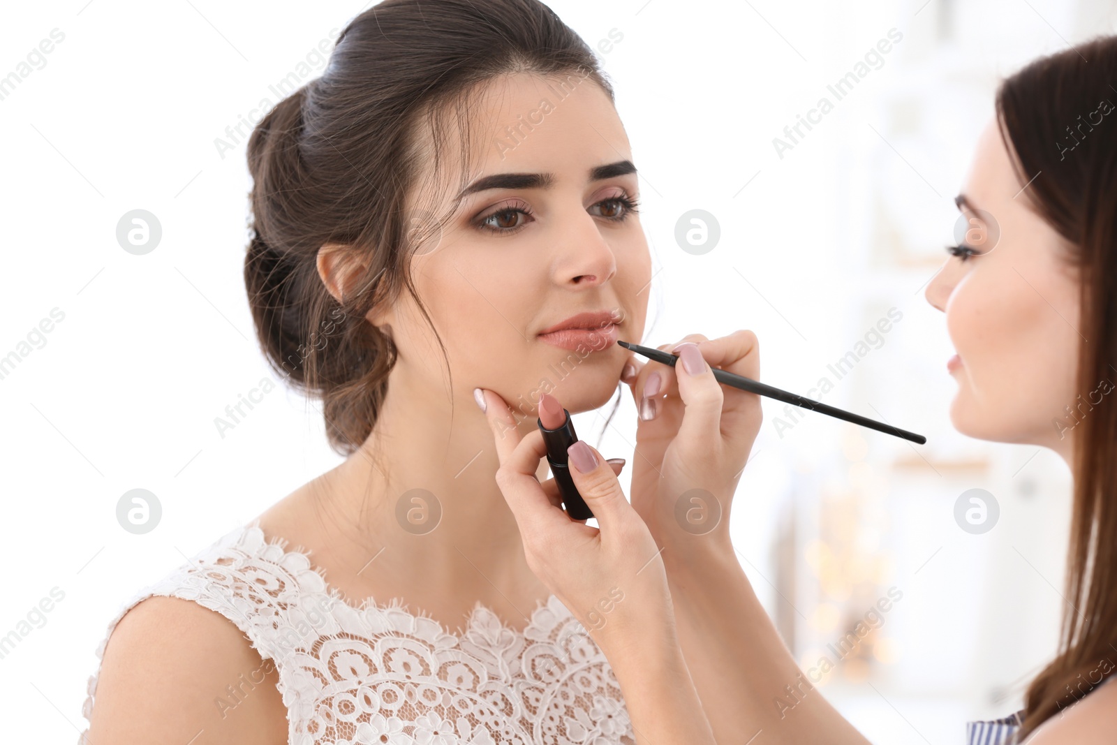 Photo of Professional makeup artist working with young woman in salon