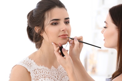 Photo of Professional makeup artist working with young woman in salon