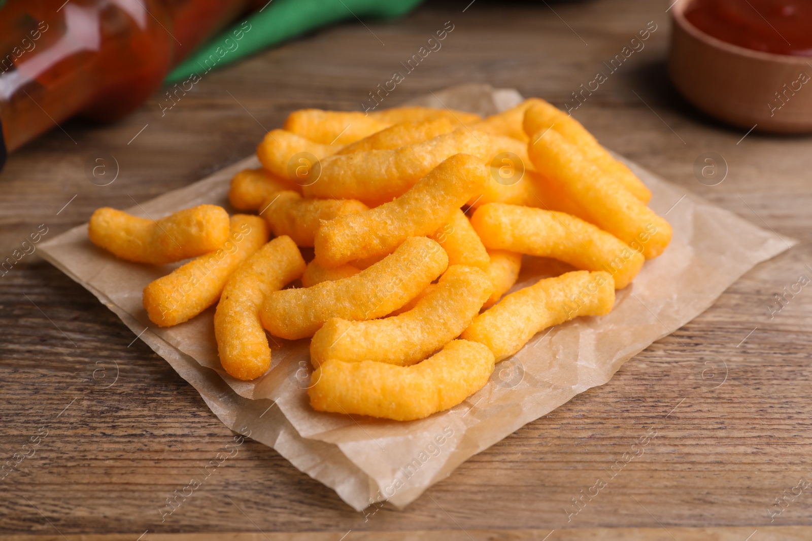 Photo of Crunchy cheesy corn snack on wooden table, closeup