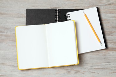 Stylish notebooks and pencil on white wooden table, flat lay