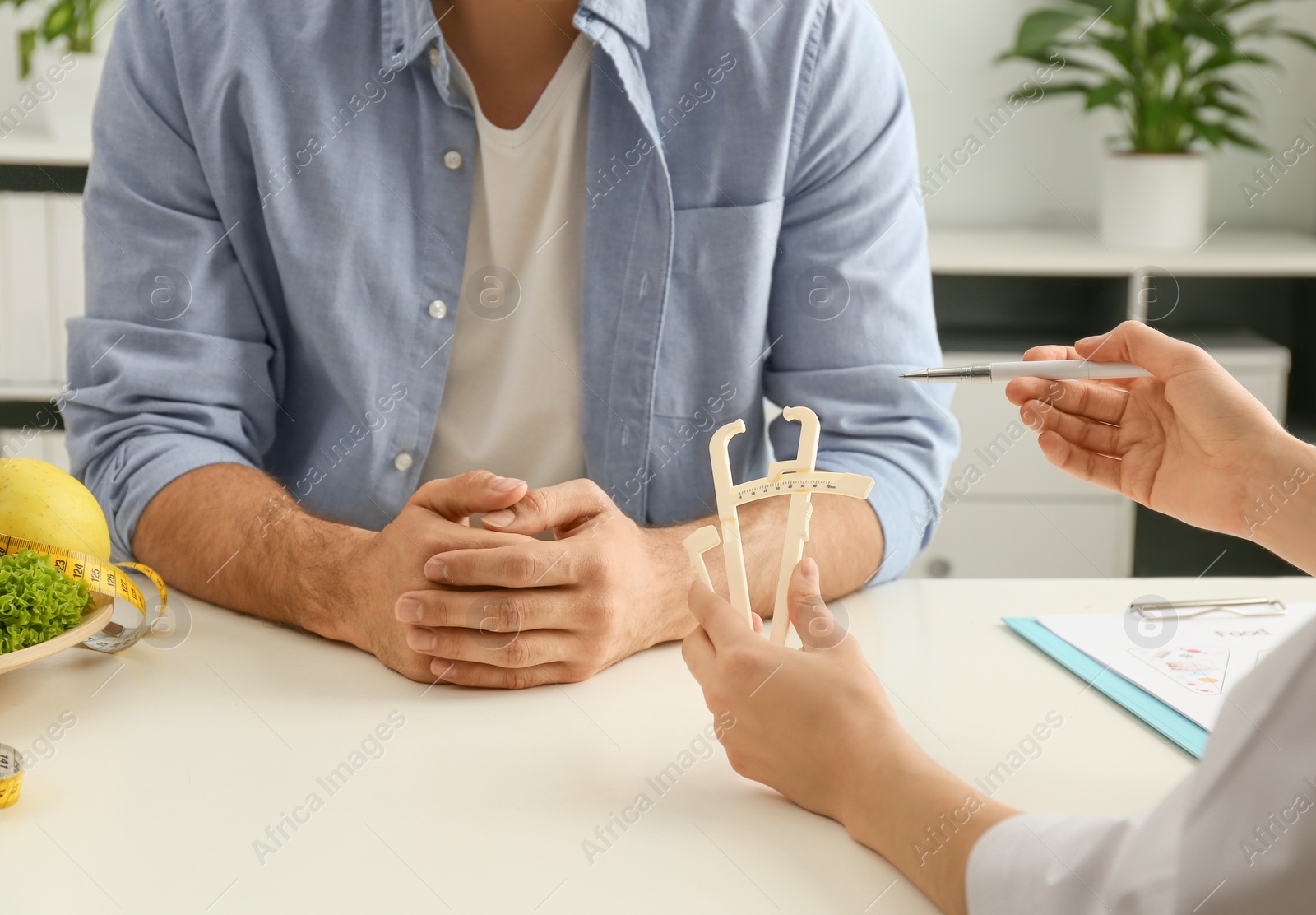 Photo of Young nutritionist consulting patient at table in clinic, closeup