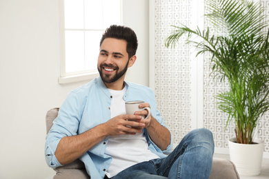 Young man with cup of drink relaxing at home