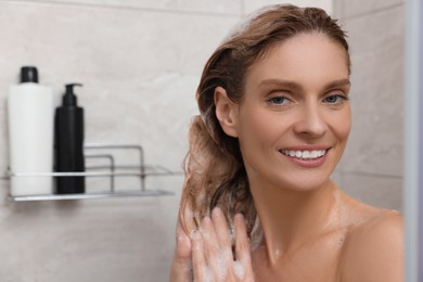Photo of Beautiful happy woman washing hair in shower. Space for text