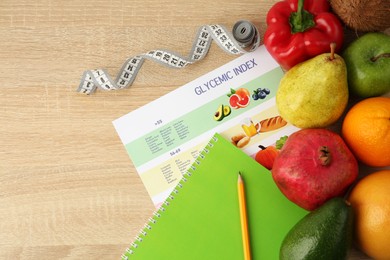 Photo of Flat lay composition with products and Glycemic index chart on wooden table, space for text