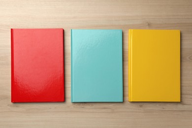 Photo of Three colorful planners on wooden table, flat lay
