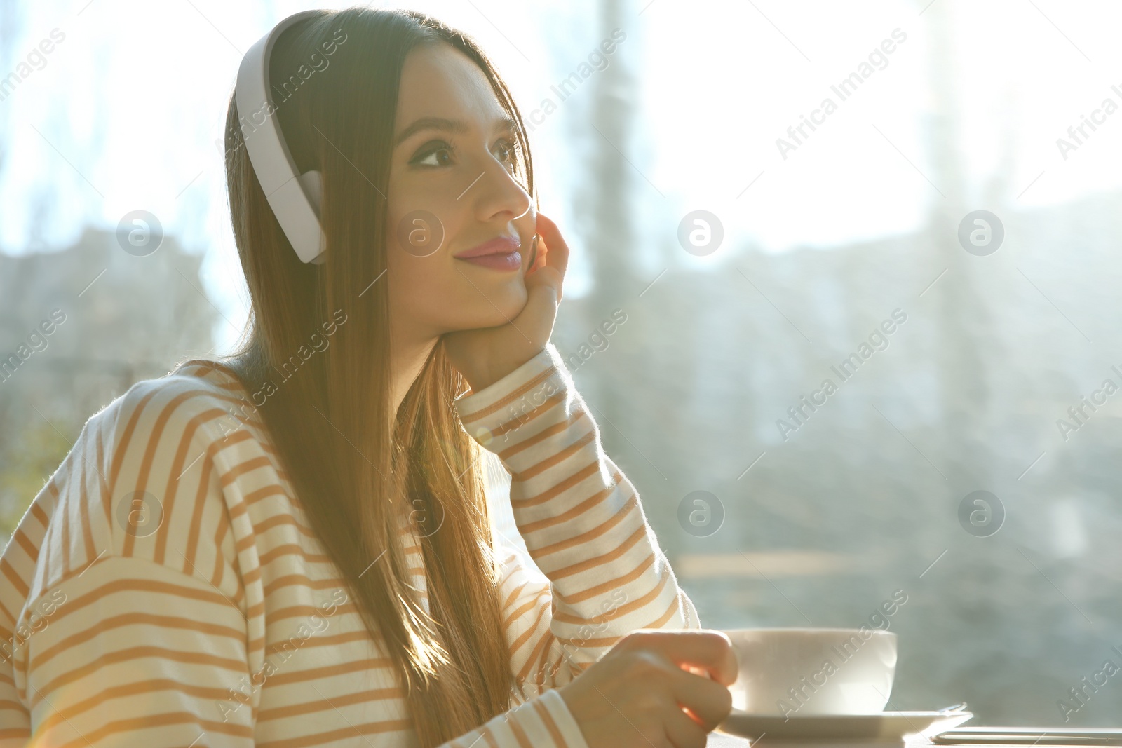 Photo of Woman listening to audiobook at table in cafe