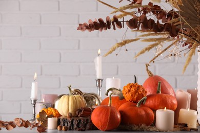 Photo of Beautiful composition with pumpkins and burning candles on table