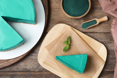 Photo of Delicious homemade spirulina cheesecake served on wooden table, top view