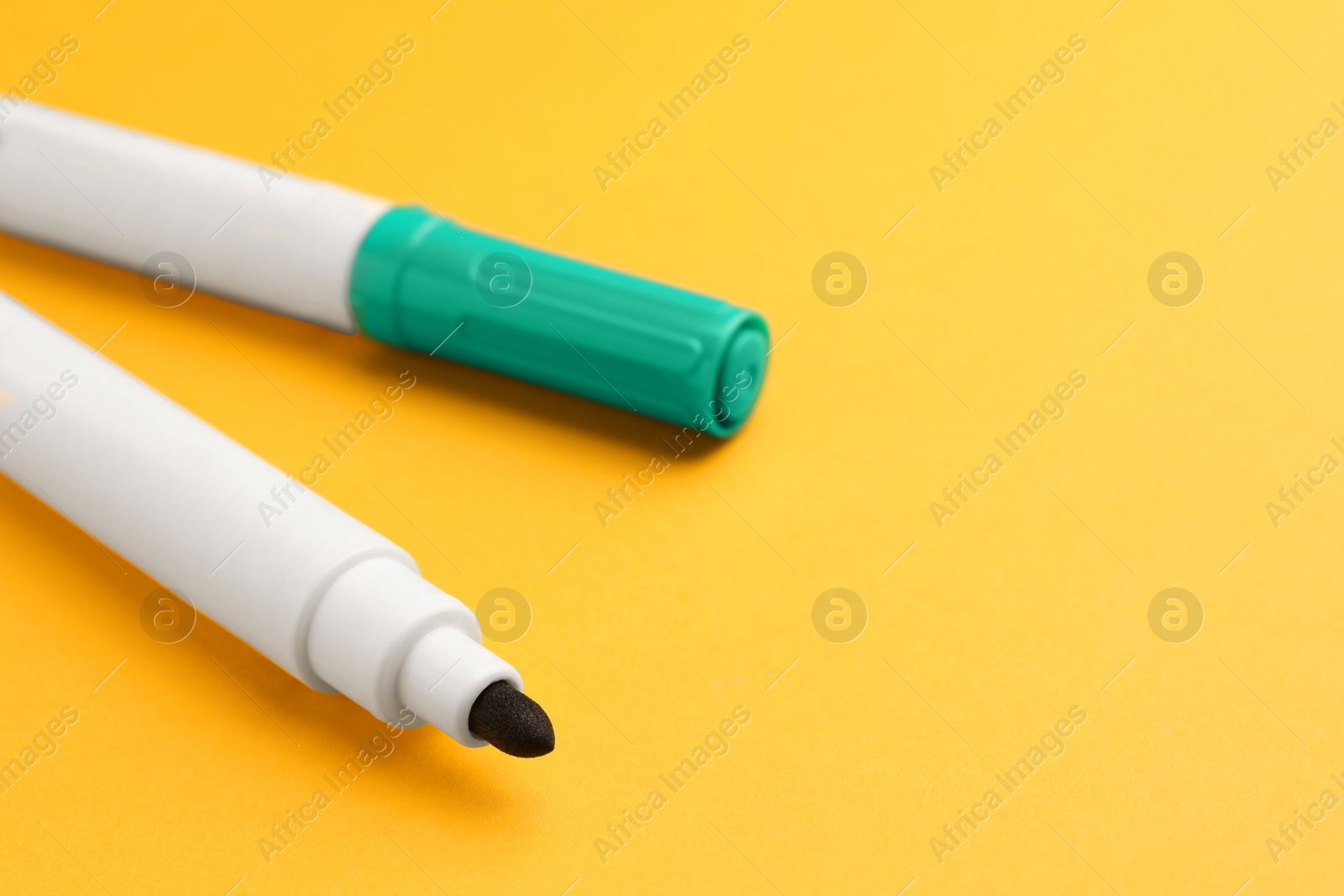 Photo of Bright color markers on orange background, closeup. Space for text