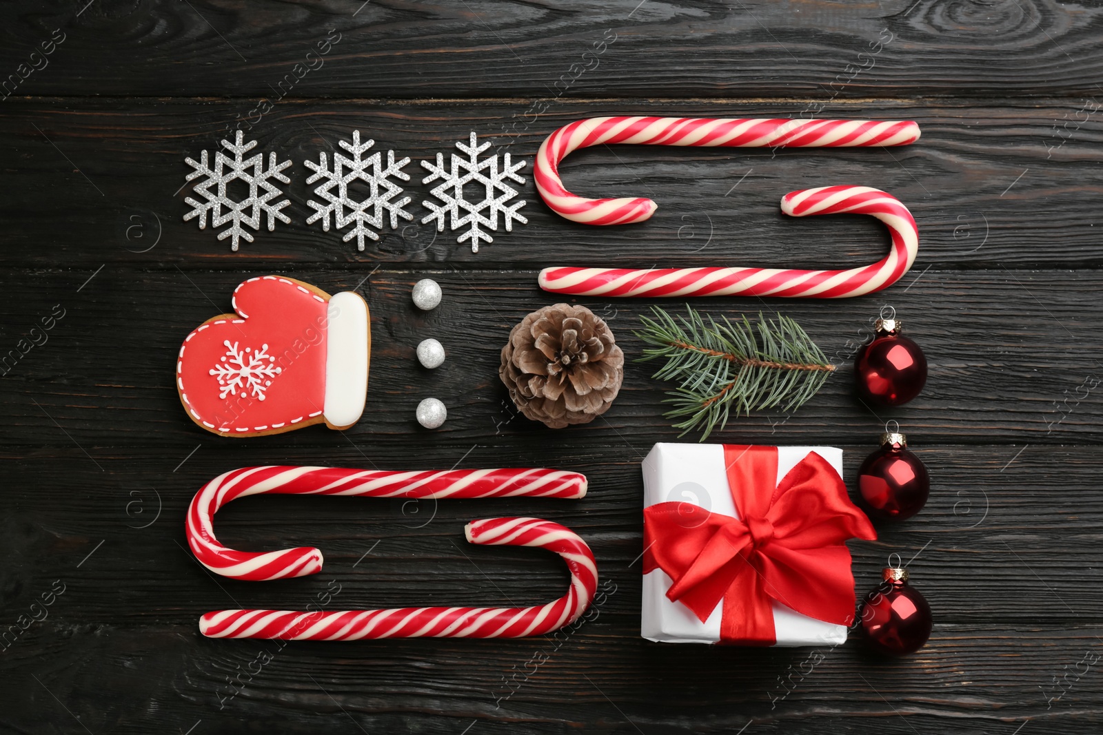 Photo of Flat lay composition with candy canes and Christmas decor on black wooden table