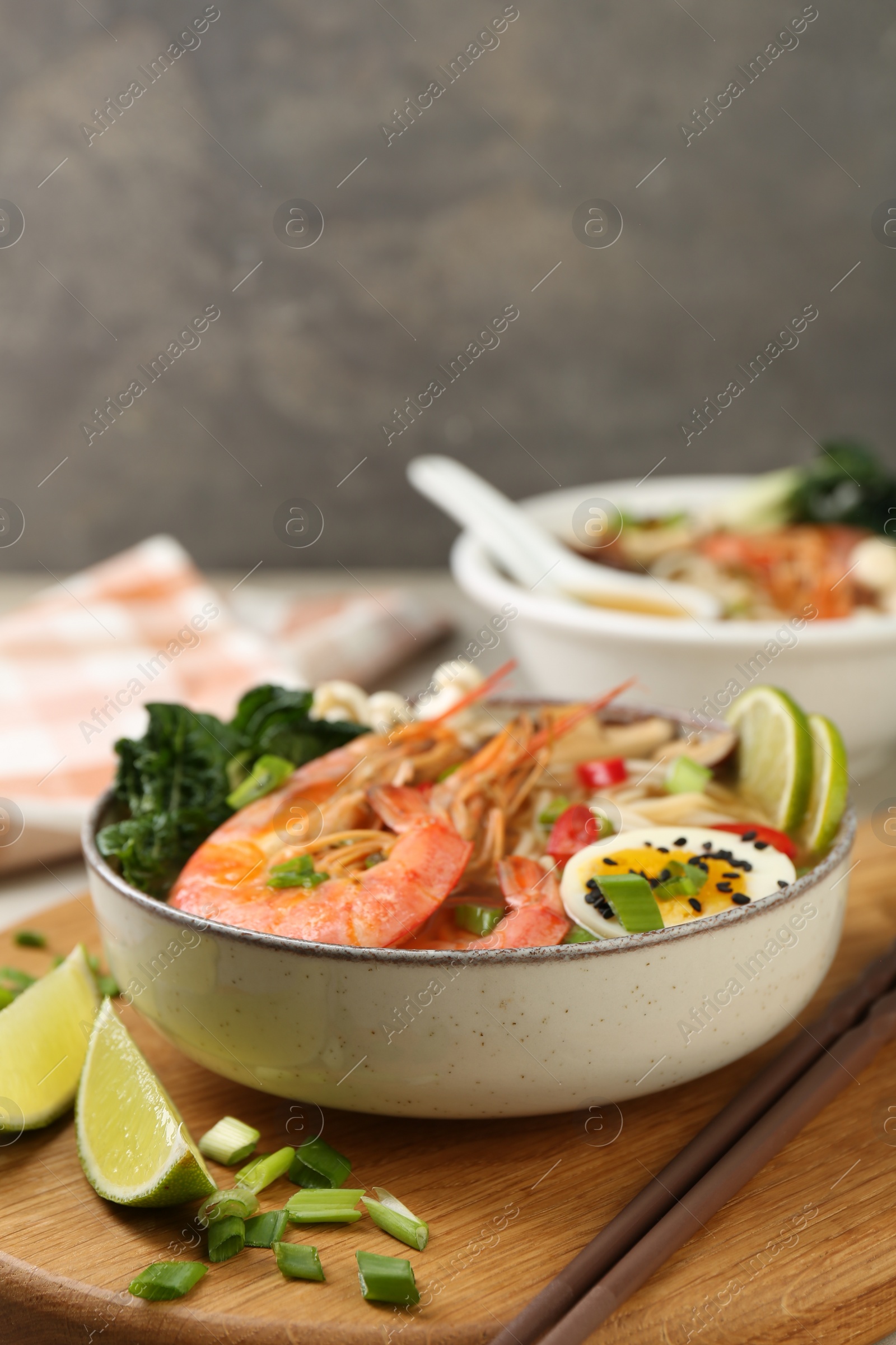 Photo of Delicious ramen with shrimps and egg in bowl served on table, closeup. Noodle soup