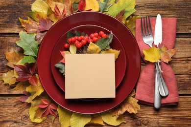 Photo of Festive table setting with autumn decor and blank card on wooden background, flat lay
