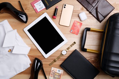 Business trip stuff and suitcase on wooden surface, flat lay