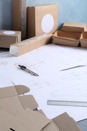 Photo of Creating packaging design. Drawings, boxes and stationery on table, closeup