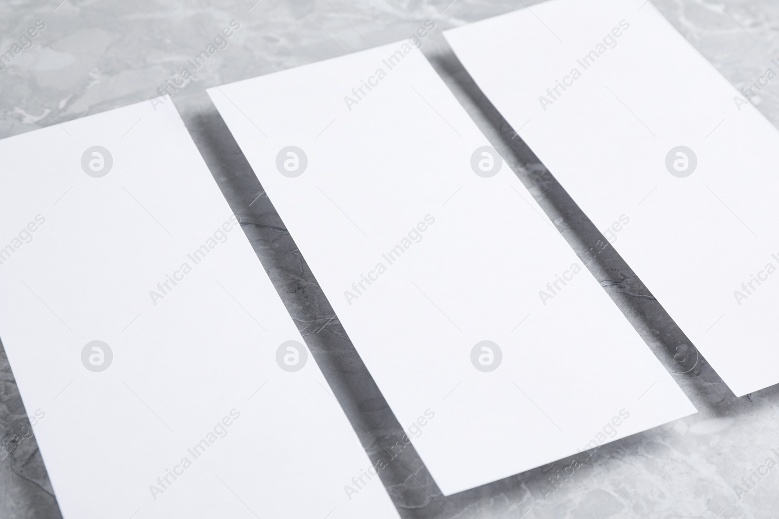 Photo of Blank palm cards on light grey marble background, closeup. Mock up for design