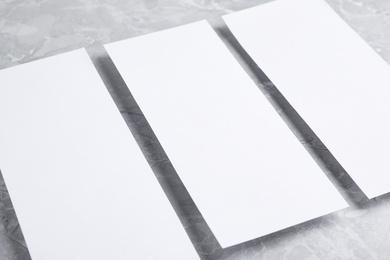 Photo of Blank palm cards on light grey marble background, closeup. Mock up for design