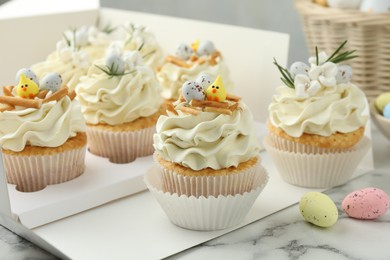 Photo of Tasty Easter cupcakes with vanilla cream on white marble table