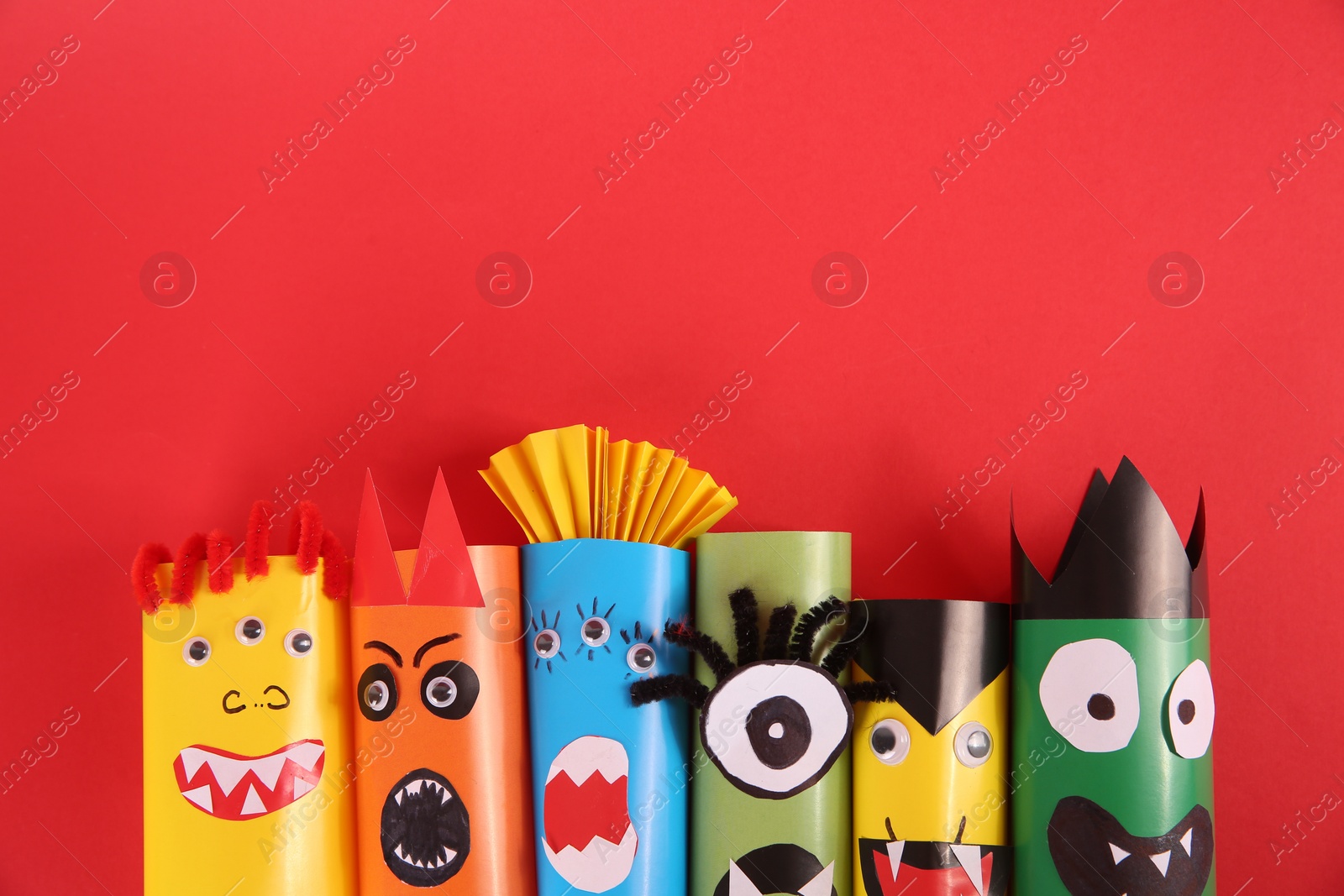 Photo of Funny monsters on red background, flat lay. Halloween decoration