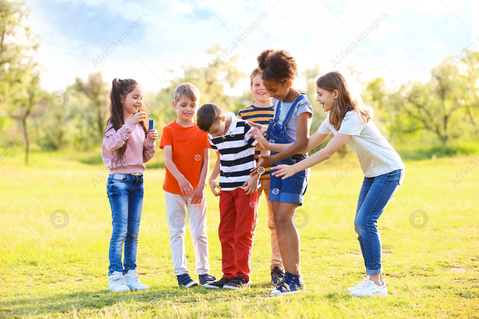 Photo of Cute little children playing with soap bubbles outdoors on sunny day