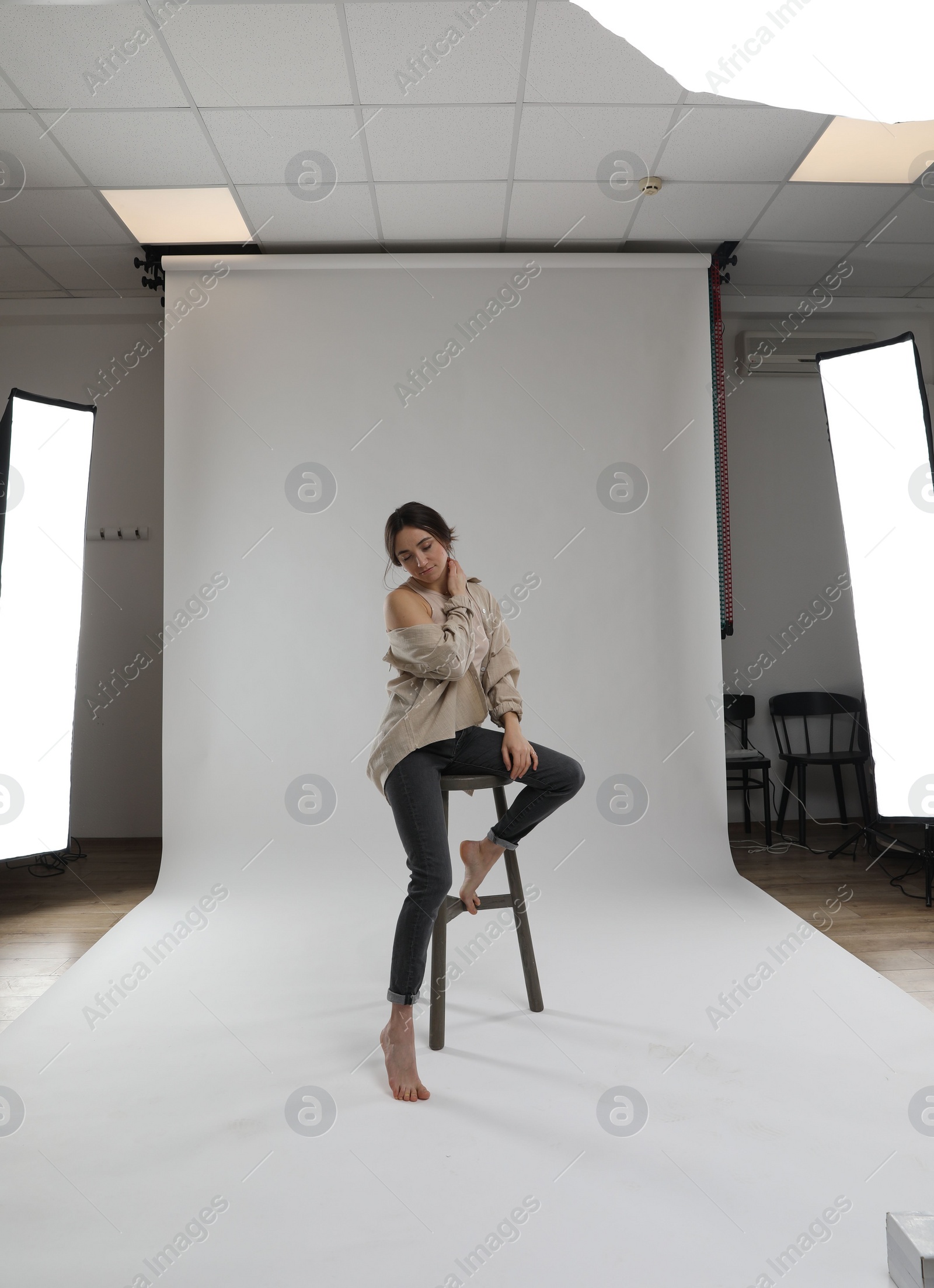 Photo of Portrait of beautiful woman sitting on chair against light grey background