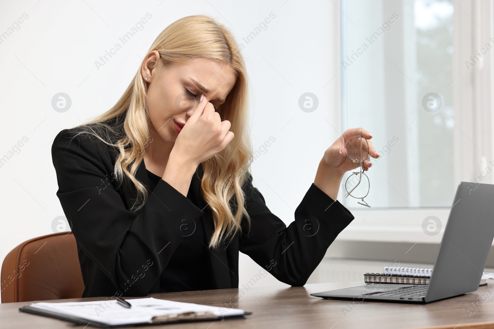 Photo of Overwhelmed woman with glasses at wooden table in office