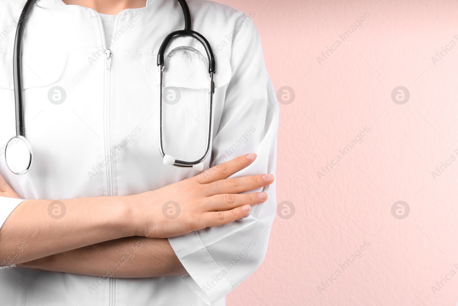 Photo of Doctor with stethoscope on pink background, closeup. Medical service