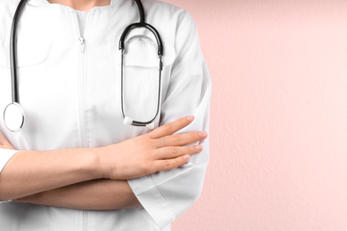 Doctor with stethoscope on pink background, closeup. Medical service