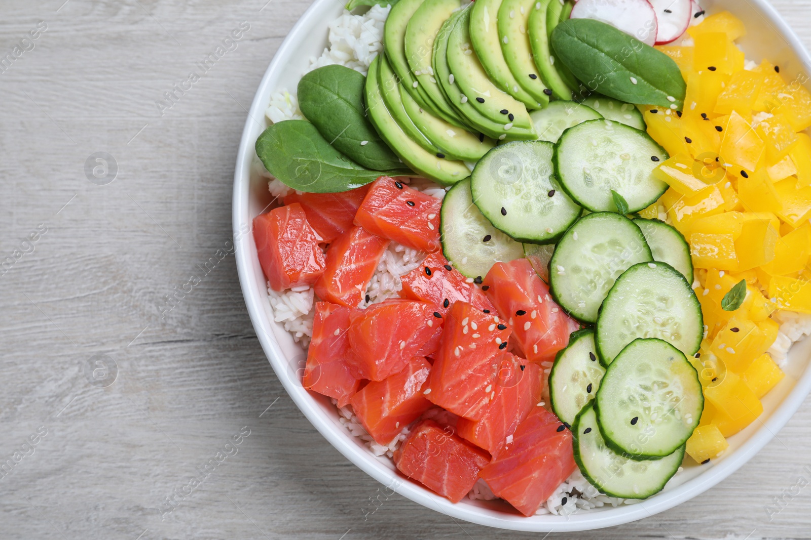 Photo of Delicious poke bowl with salmon and vegetables on wooden table, top view