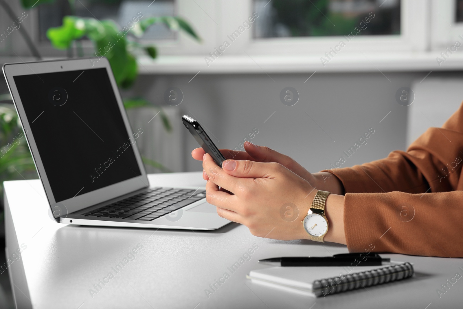 Photo of Woman using smartphone at table in office, closeup