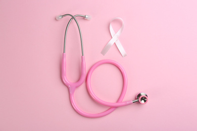 Pink ribbon as breast cancer awareness symbol and stethoscope on color background, flat lay